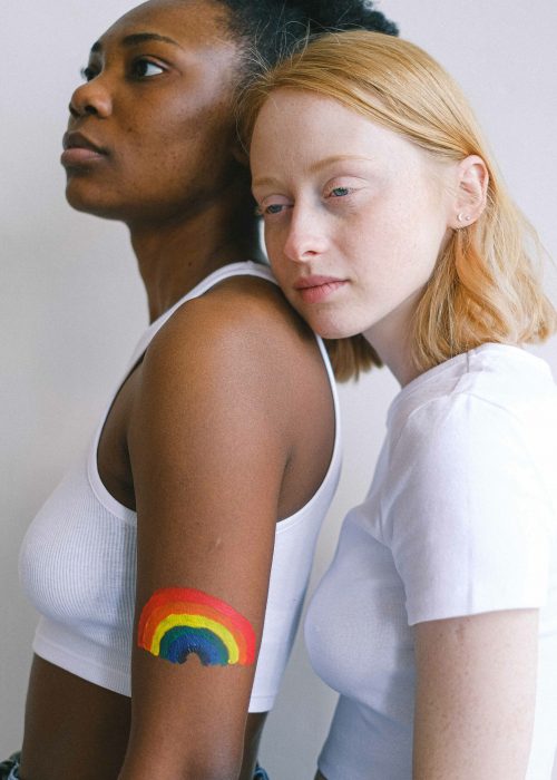 Ava und Maya stehen seitlich hintereinander, Ava hat aufgemalten Regenbogen am linken Arm